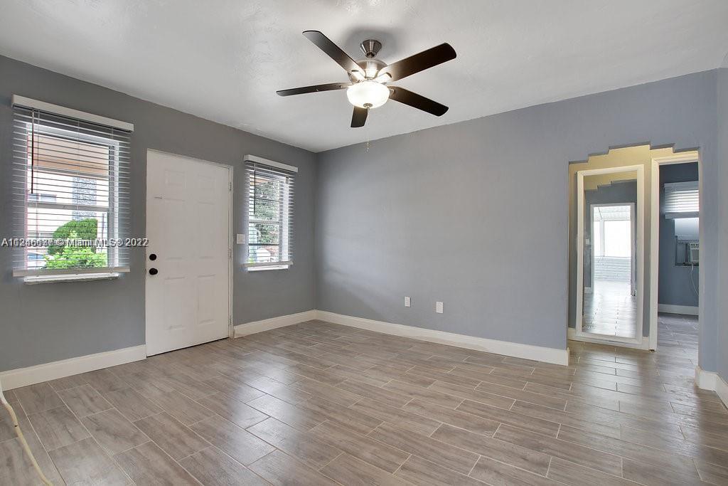 154 Southwest 18th Court Miami, FL 33135 - Photo 6 of 9 an empty room with wooden floor chandelier fan and windows
