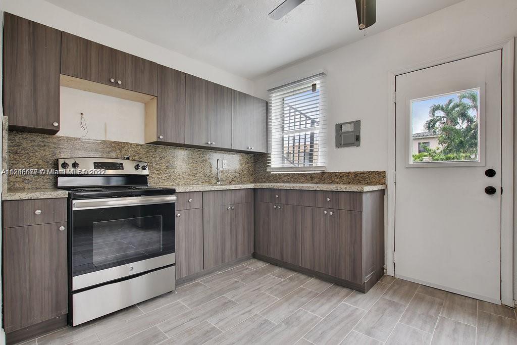 154 Southwest 18th Court Miami, FL 33135 - Photo 7 of 9 a kitchen with granite countertop wooden cabinets and white appliances