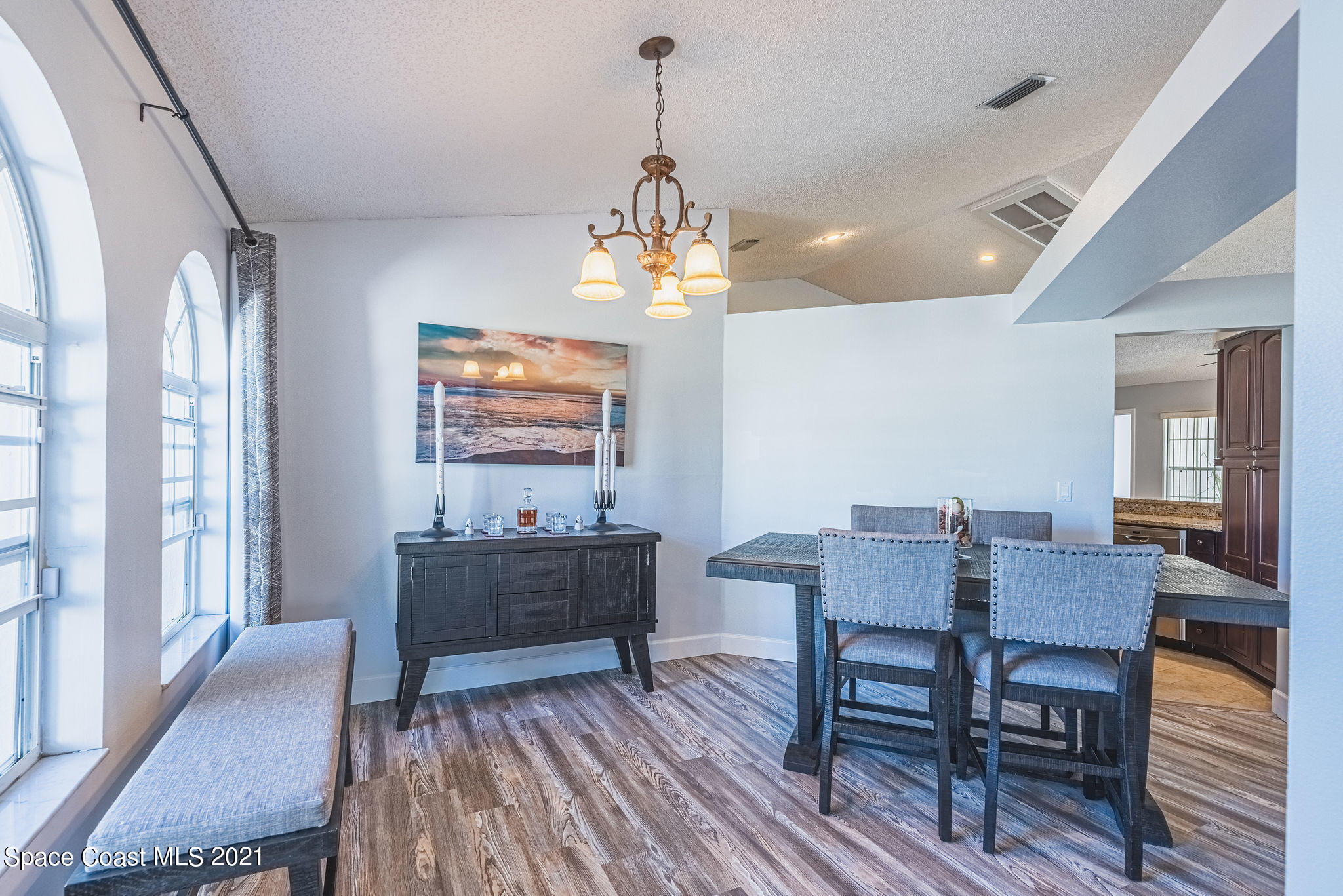 7207 Achilles Road Cocoa, FL 32927 - Photo 3 of 57 a dining room with wooden floor a chandelier a wooden table and chairs
