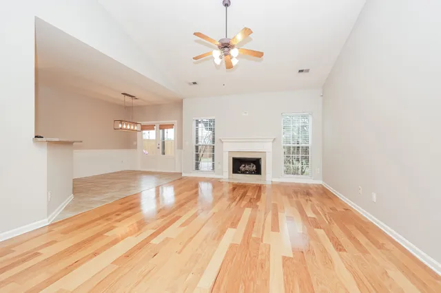 a view of an empty room with wooden floor and a fireplace