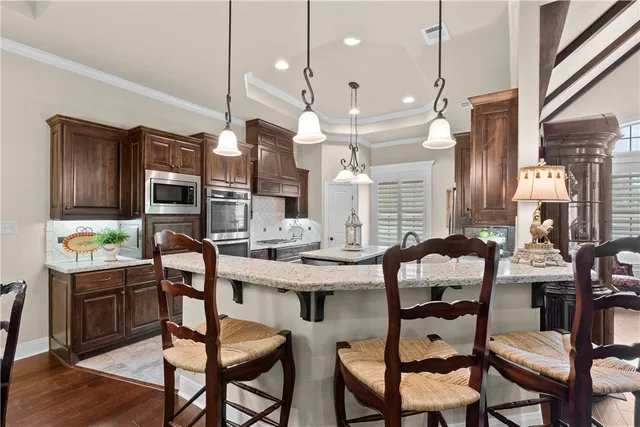 a room with granite countertop lots of wooden furniture and stainless steel appliances