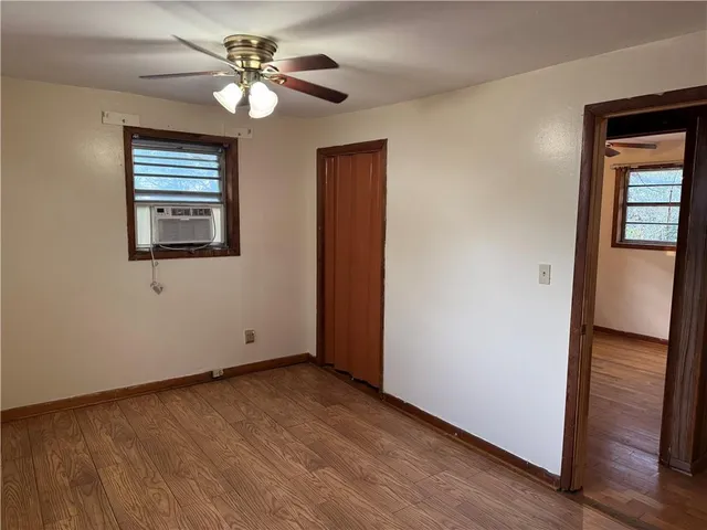 a view of an empty room with a window and wooden floor