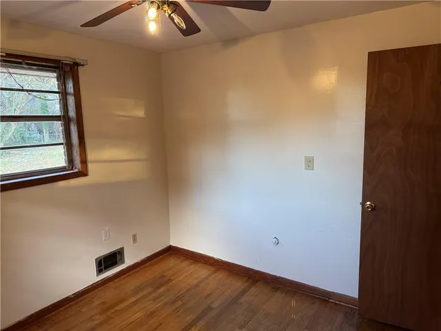 an empty room with wooden floor closet and fan