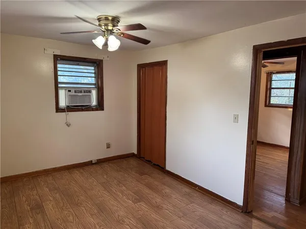 an empty room with wooden floor closet and fan