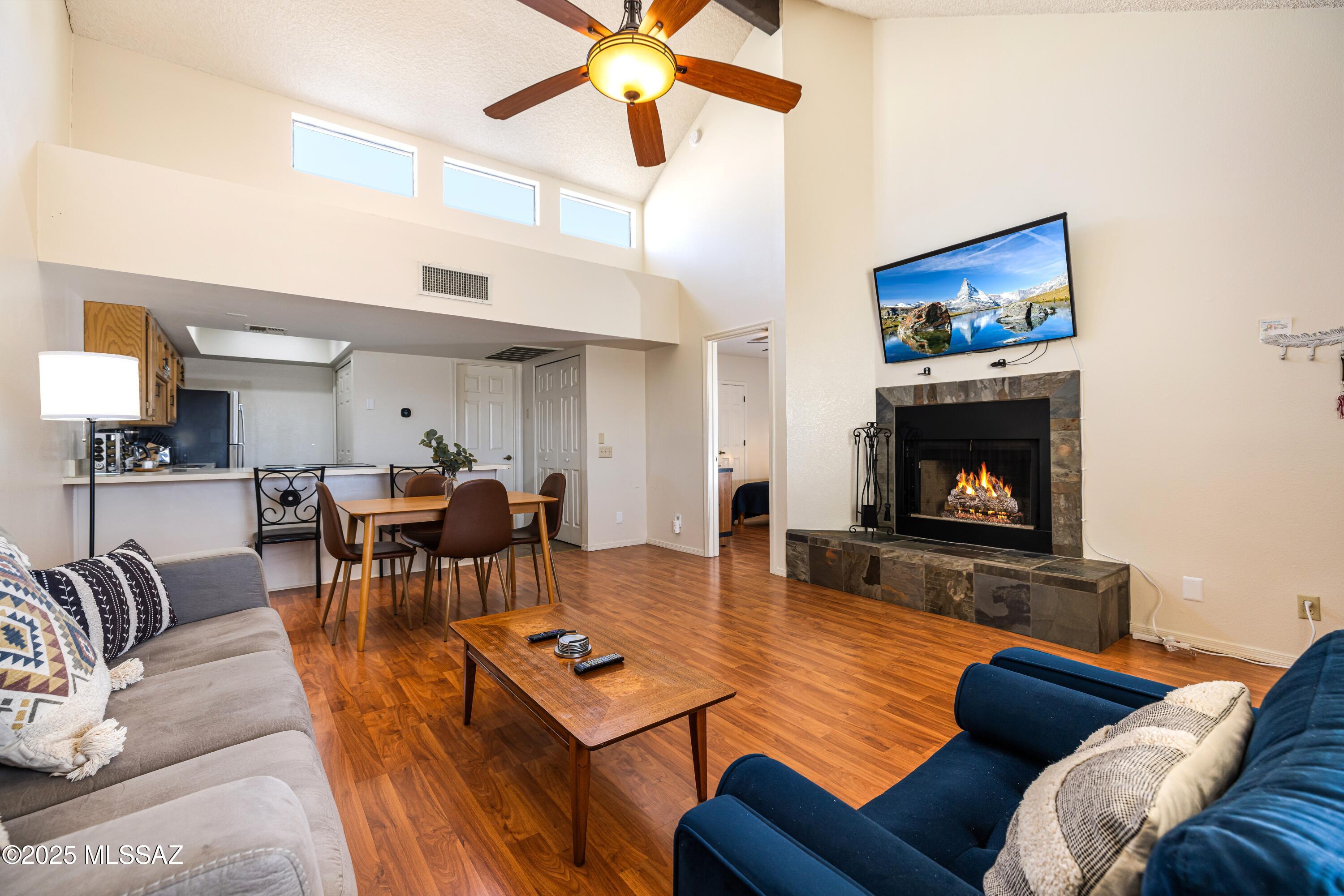 1200 East River Road, Unit G88 Tucson, AZ 85718 - Photo 2 of 13 a living room with furniture a fireplace and a chandelier