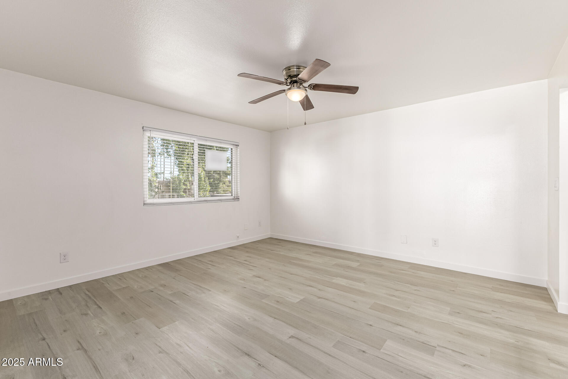 7126 North 19th Avenue, Unit 224 Phoenix, AZ 85021 - Photo 22 of 37 an empty room with wooden floor ceiling fan and windows