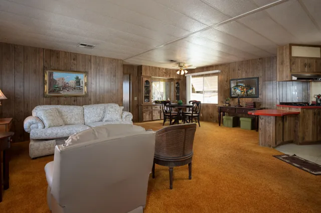 a living room with furniture kitchen view and a wooden floor