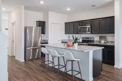 a kitchen with stainless steel appliances granite countertop a refrigerator a stove a sink a dining table and chairs