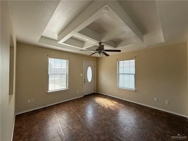 en empty room with windows and ceiling fan