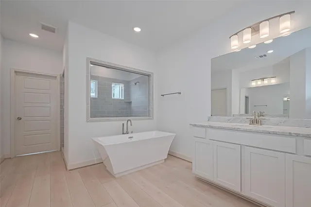 a spacious bathroom with a double vanity sink mirror and bathtub