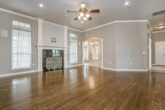 a view of an empty room with window and wooden floor