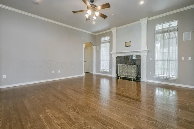 a view of an empty room with window and wooden floor