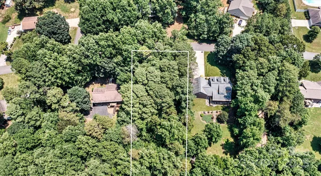 an aerial view of residential house with outdoor space and trees all around
