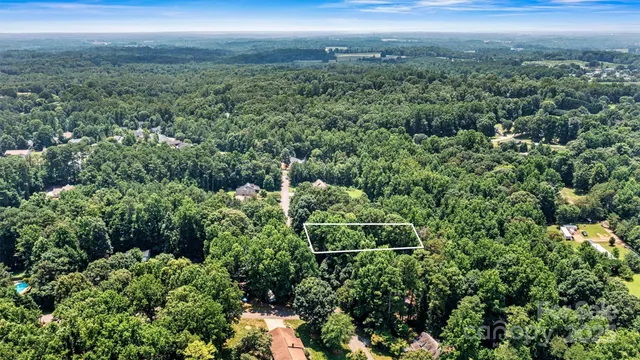 an aerial view of residential house with outdoor space and trees all around