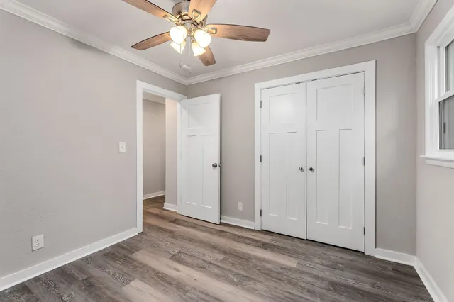 a view of empty room with wooden floor and fan