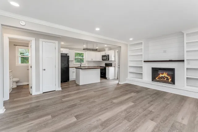 a view of a livingroom with a fireplace a ceiling fan and windows