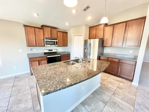 a kitchen with stainless steel appliances granite countertop wooden cabinets a stove a sink and a oven