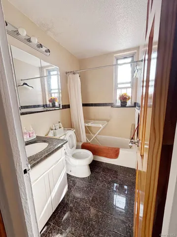 a bathroom with a granite countertop sink toilet and mirror