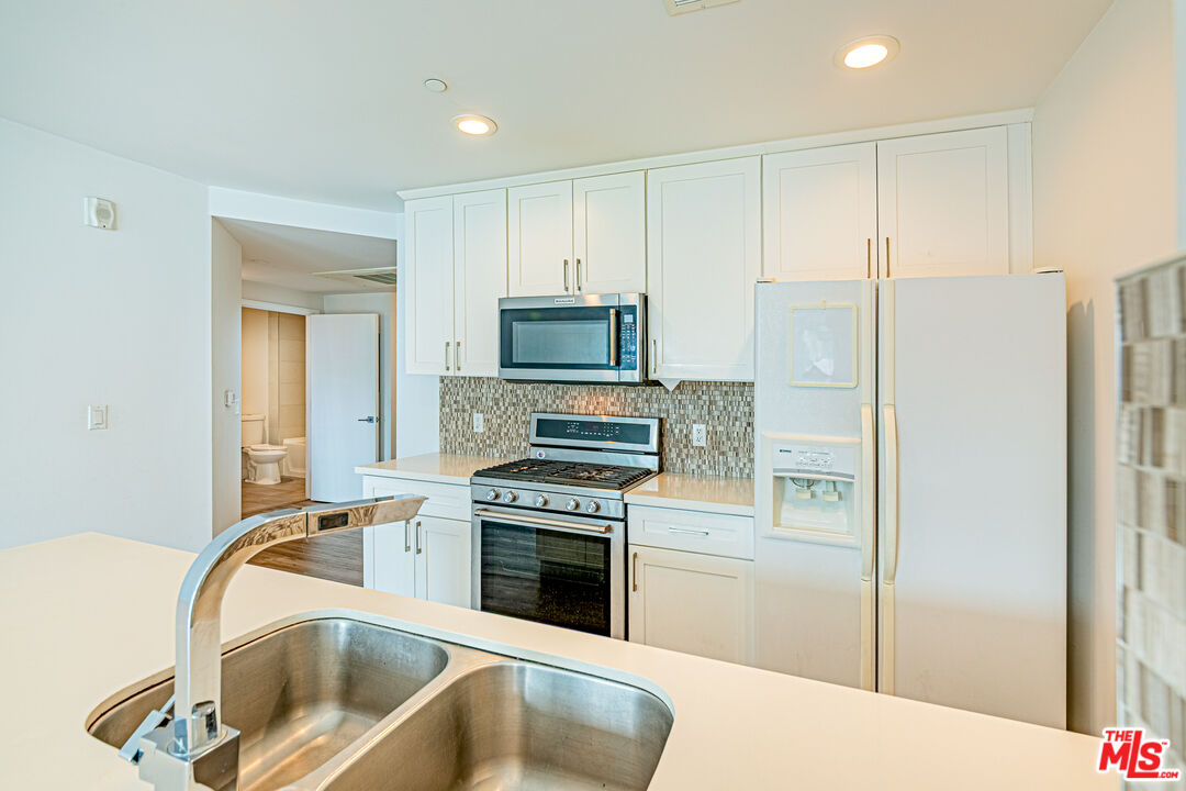 1101 South Harvard Boulevard, Unit 303 Los Angeles, CA 90006 - Photo 11 of 44 a kitchen with a refrigerator a stove a microwave and a sink