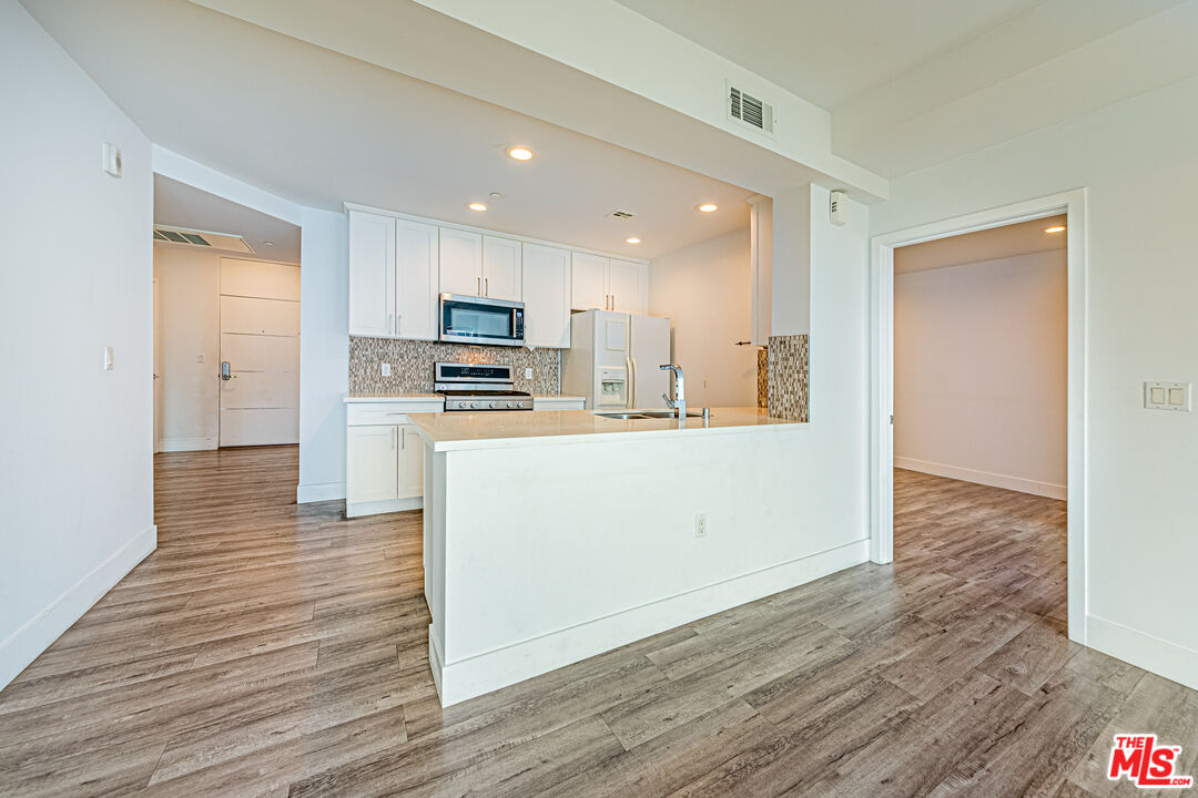 1101 South Harvard Boulevard, Unit 303 Los Angeles, CA 90006 - Photo 7 of 44 a kitchen with stainless steel appliances granite countertop a refrigerator a sink dishwasher and a oven with white cabinets