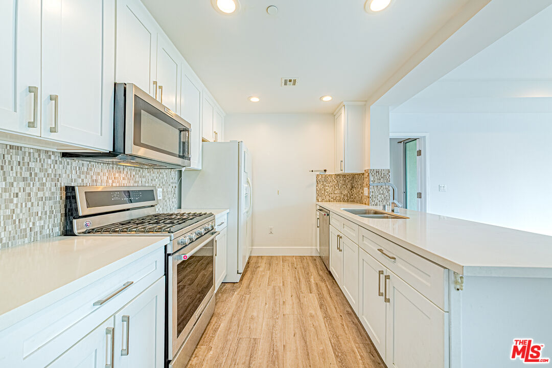 1101 South Harvard Boulevard, Unit 303 Los Angeles, CA 90006 - Photo 9 of 44 a kitchen with stainless steel appliances granite countertop a stove and a sink