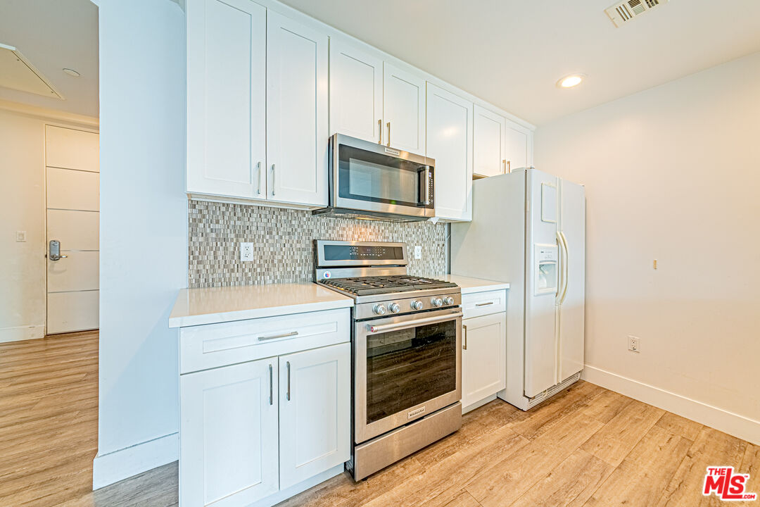 1101 South Harvard Boulevard, Unit 303 Los Angeles, CA 90006 - Photo 10 of 44 a kitchen with stainless steel appliances white cabinets and a stove top oven