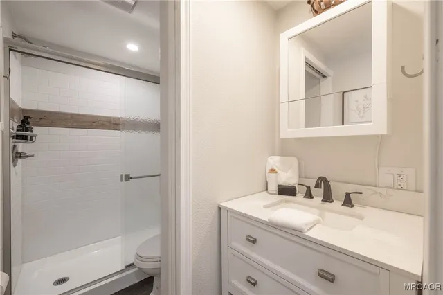 a bathroom with a granite countertop sink mirror vanity and toilet