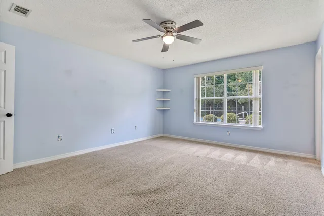 an empty room with windows and ceiling fan