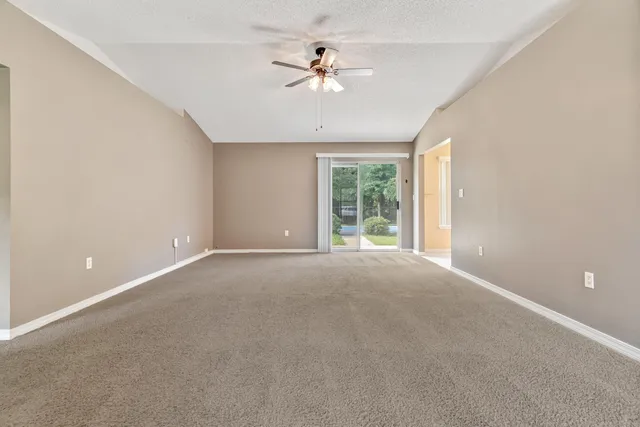 an empty room with chandelier fan and window