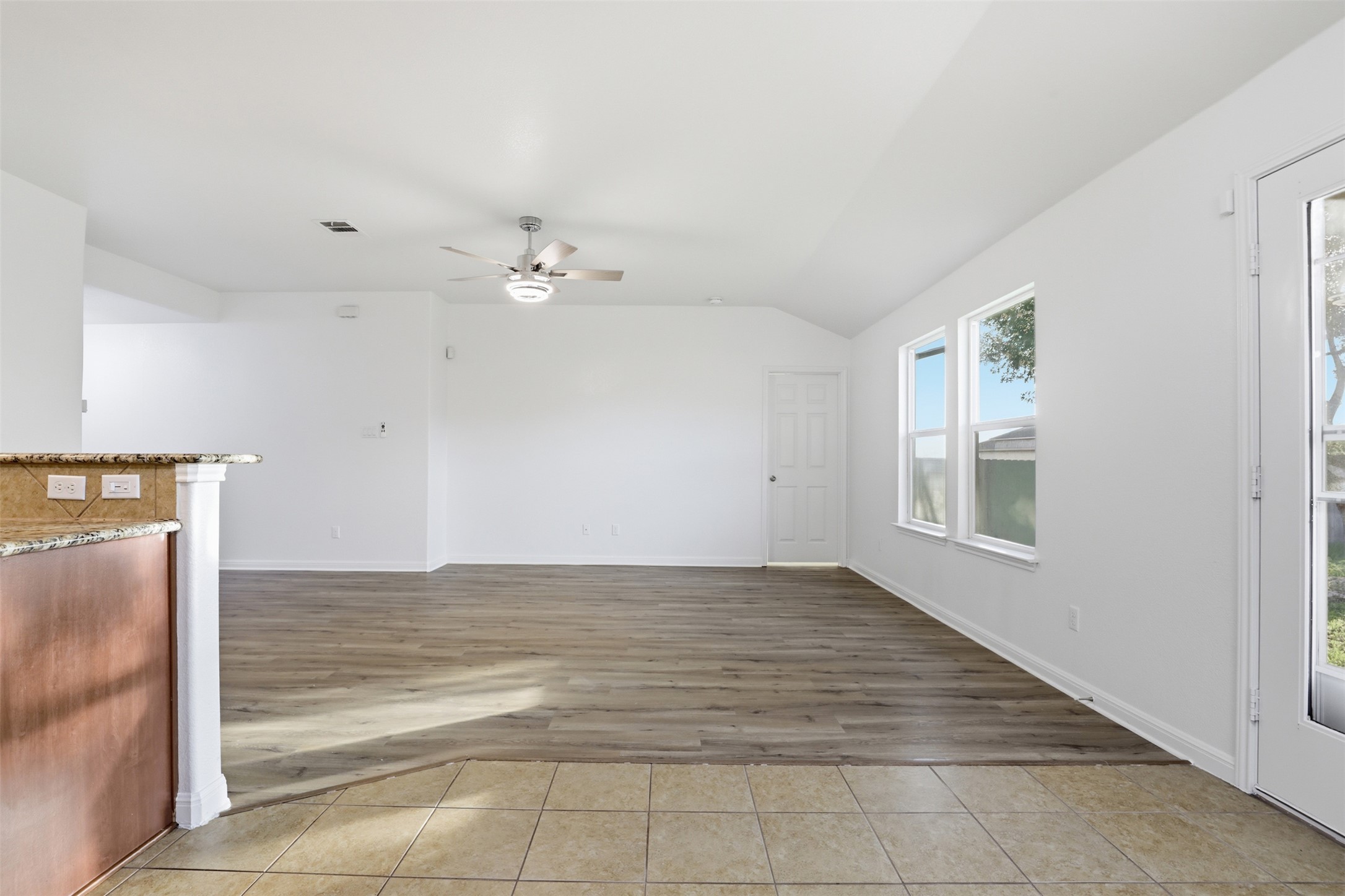 448 Nottingham Loop Kyle, TX 78640 - Photo 5 of 16 Open-concept living area featuring wood-finish flooring, vaulted ceilings, and a ceiling fan with integrated lighting