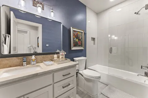 a bathroom with a toilet a sink a tub and mirror
