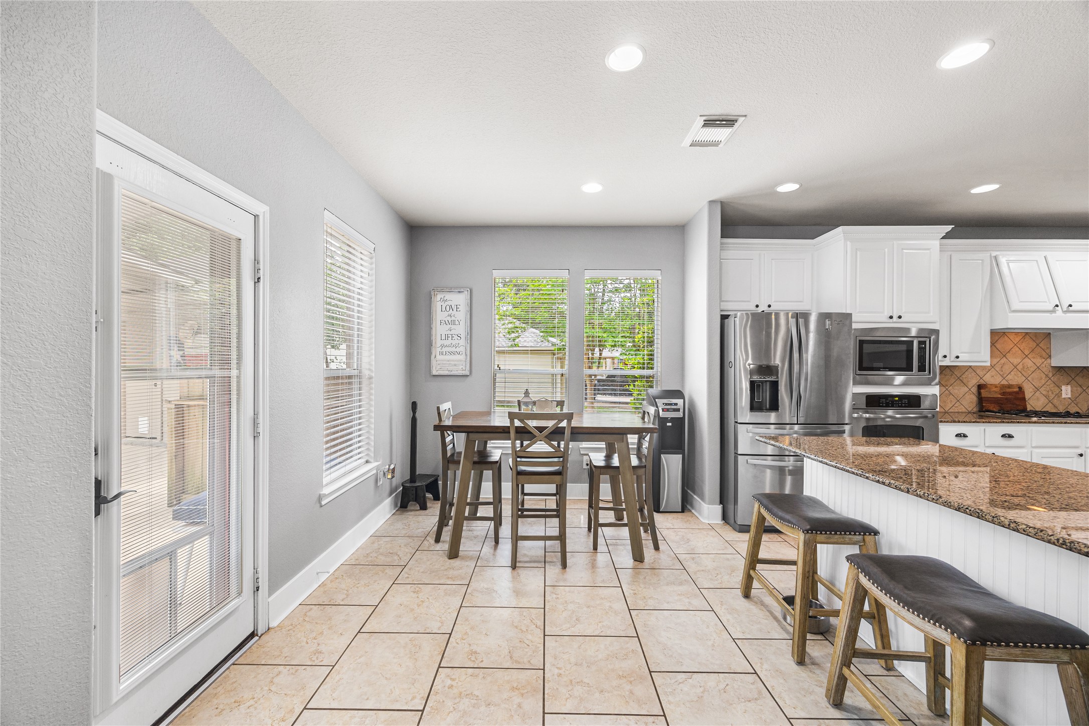 2167 Summit Mist Drive Conroe, TX 77304 - Photo 12 of 34 a kitchen with stainless steel appliances granite countertop a stove top oven a sink dishwasher a dining table and chairs with wooden floor