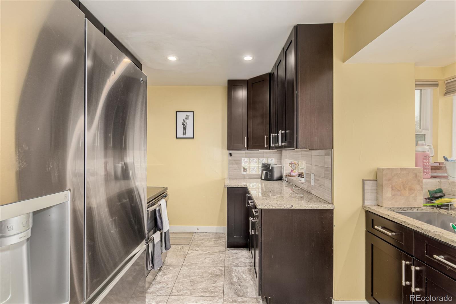 3650 Oneida Street Denver, CO 80207 - Photo 12 of 28 a kitchen with stainless steel appliances granite countertop a refrigerator and a sink