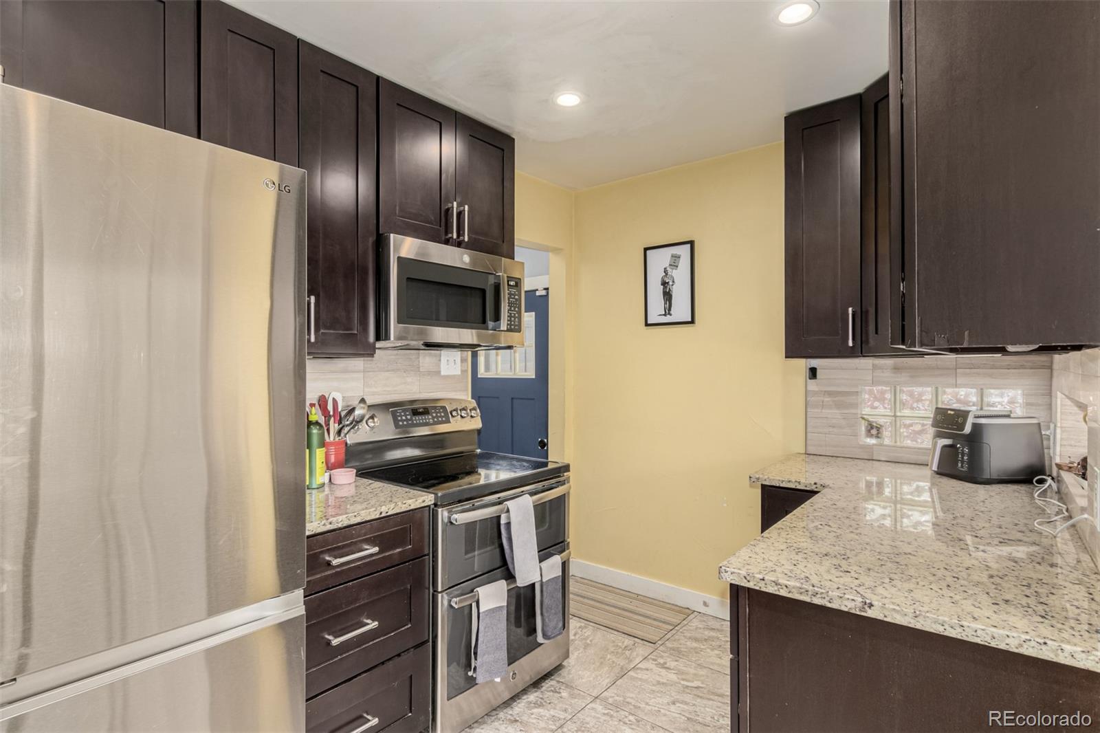 3650 Oneida Street Denver, CO 80207 - Photo 8 of 31 a kitchen with stainless steel appliances granite countertop a refrigerator and a sink