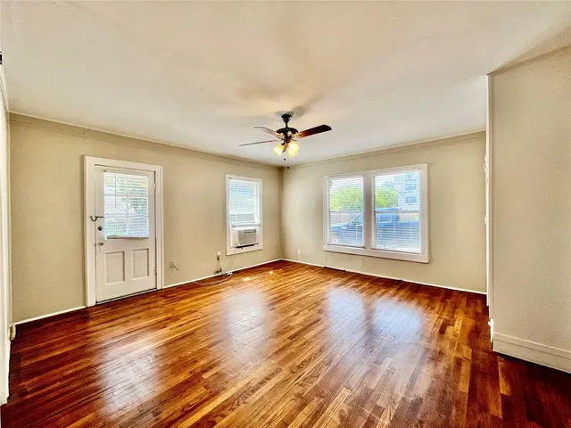 a view of an empty room with wooden floor and a window