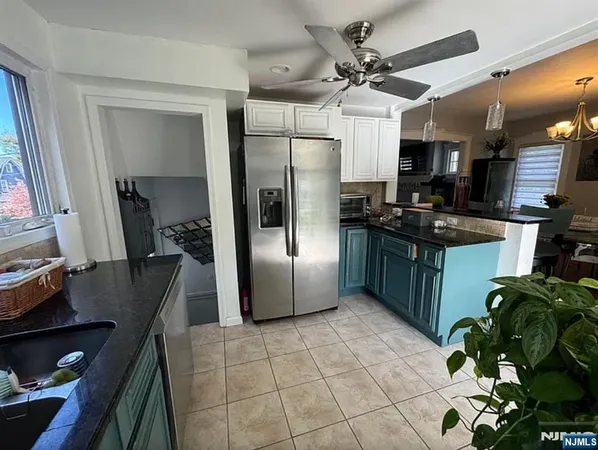 a kitchen with stainless steel appliances granite countertop a refrigerator a sink a stove white cabinets a dining table and chairs