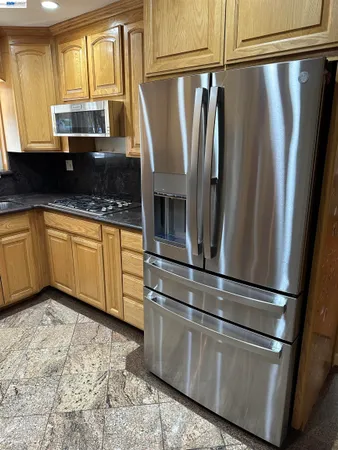 a kitchen with stainless steel appliances granite countertop a refrigerator a sink and a granite counter tops