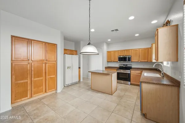 a kitchen with stainless steel appliances granite countertop a refrigerator a sink a stove top oven a counter space and cabinets