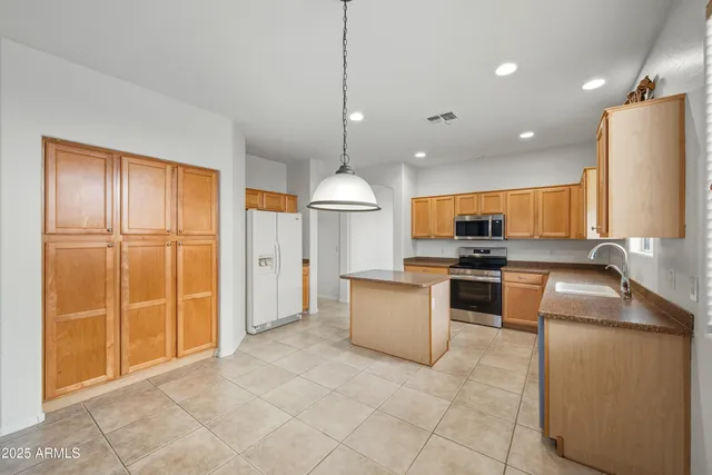 a kitchen with stainless steel appliances granite countertop a refrigerator a sink a stove top oven a counter space and cabinets