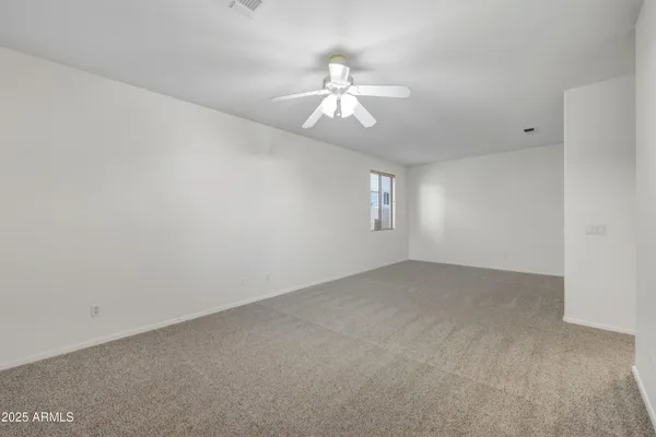 an empty room with windows and chandelier fan