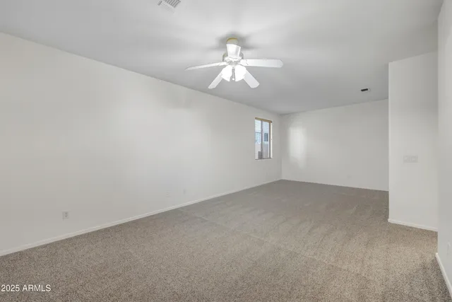 an empty room with windows and chandelier fan