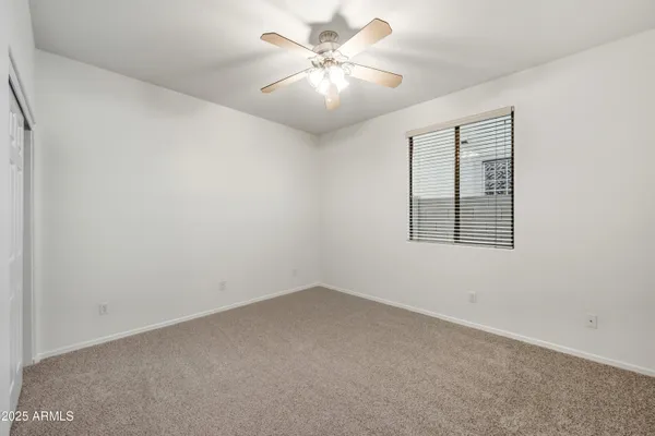 an empty room with a chandelier fan and windows