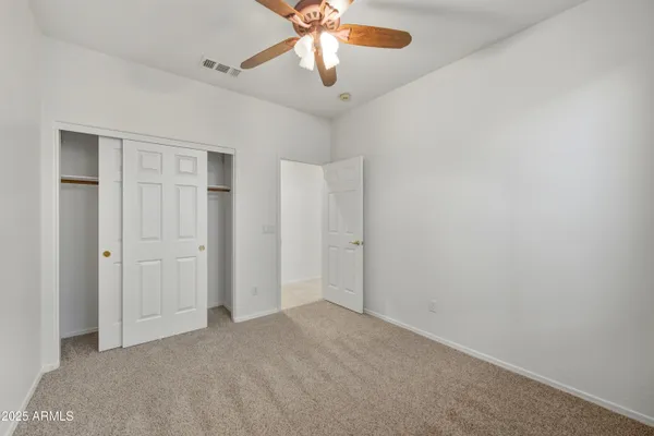 a view of an empty room and chandelier fan