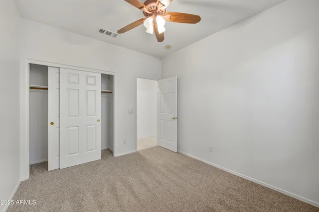 a view of an empty room and chandelier fan