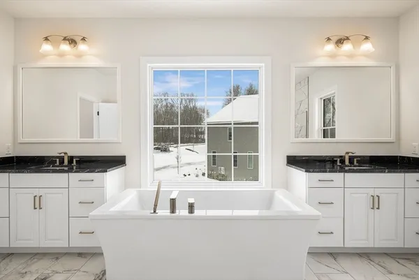 a bathroom with white cabinets granite and a sink