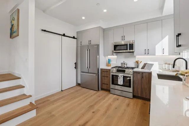 a kitchen with stainless steel appliances a stove a sink and a refrigerator