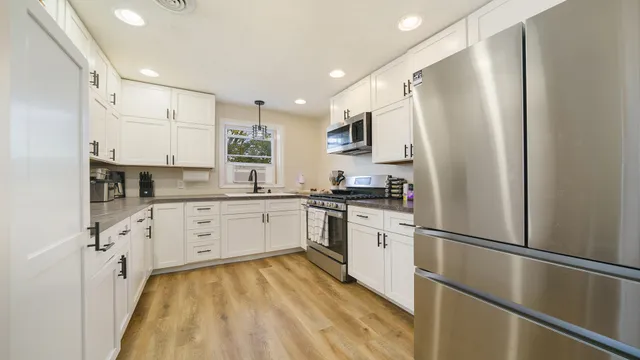 a kitchen with white cabinets stainless steel appliances and white appliances