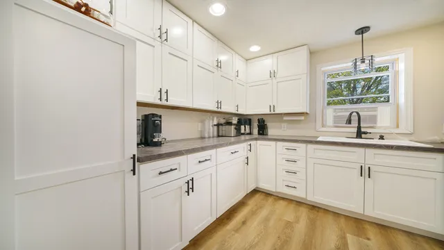 a kitchen with stainless steel appliances granite countertop a sink a stove and white cabinets with wooden floor