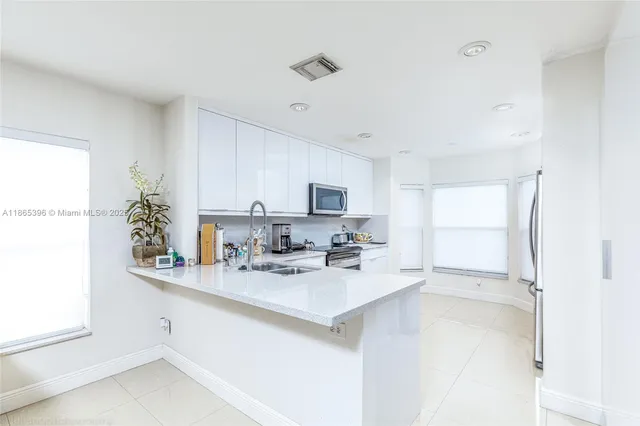 a kitchen with stainless steel appliances a sink a stove a refrigerator and cabinets