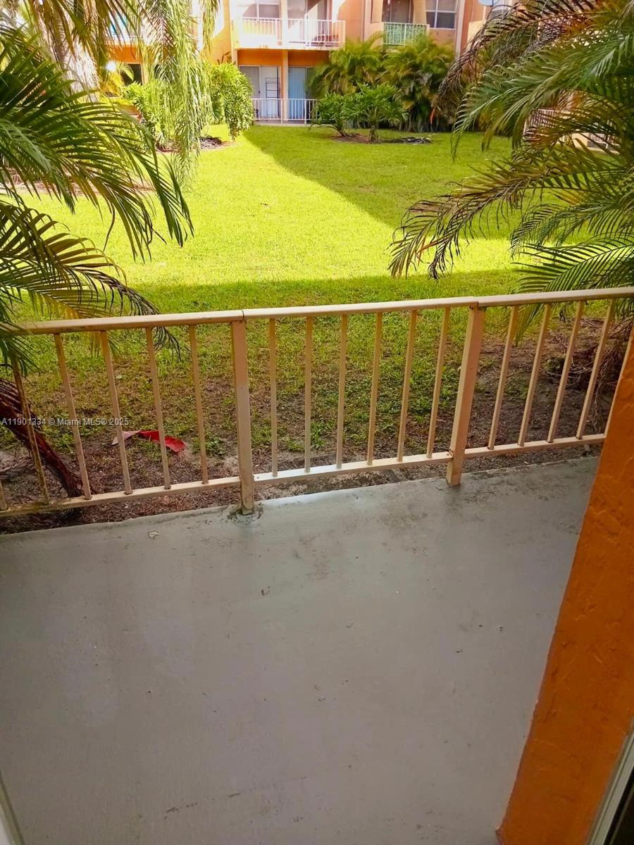 18051 Northwest 68th Avenue, Unit J102 Hialeah, FL 33015 - Photo 15 of 15 a view of a balcony with a floor to ceiling window and tree